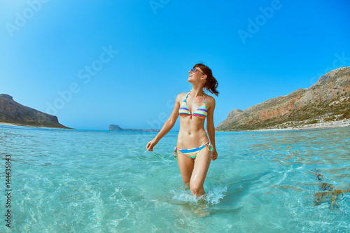 beautiful sexy woman dressed in bikini walking on the beach along the sea front. vacation and travel photography concept