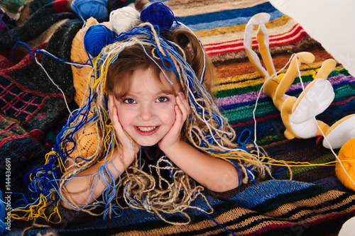 Tableau sur toile Little girls play with balls of wool.