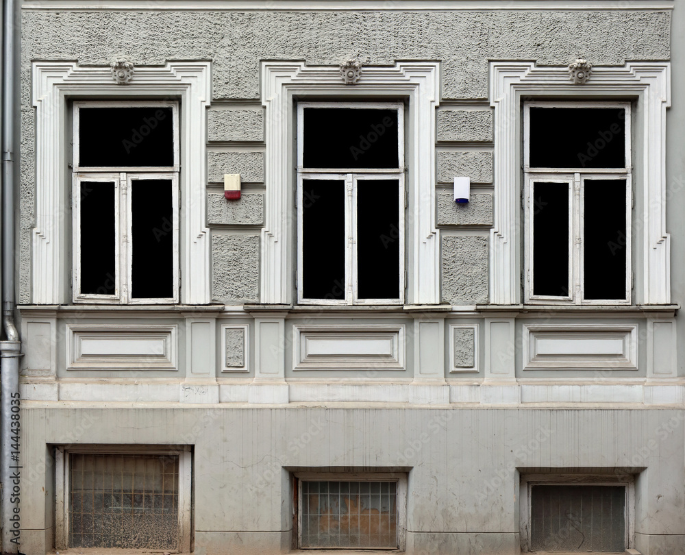 Three windows with decorative stone frames in the house stylized by a retro.