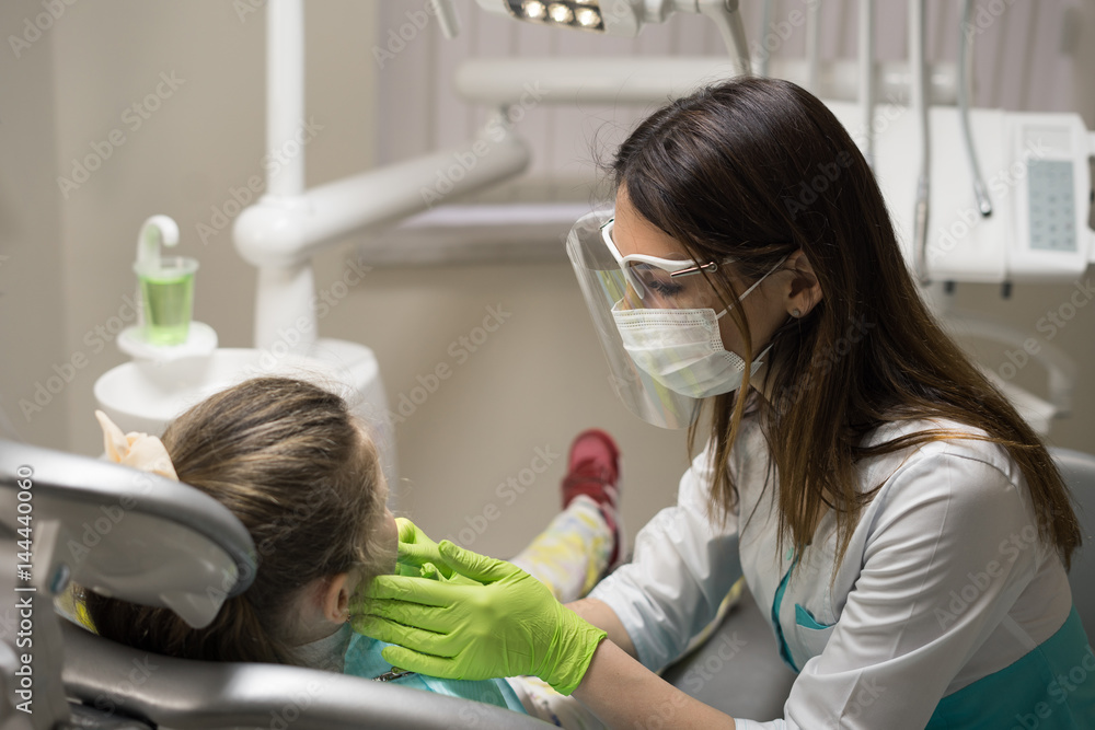 Female Dentist checking little girl patient at dental clinic. Female Dentist checking little girl patient at dental clinic.