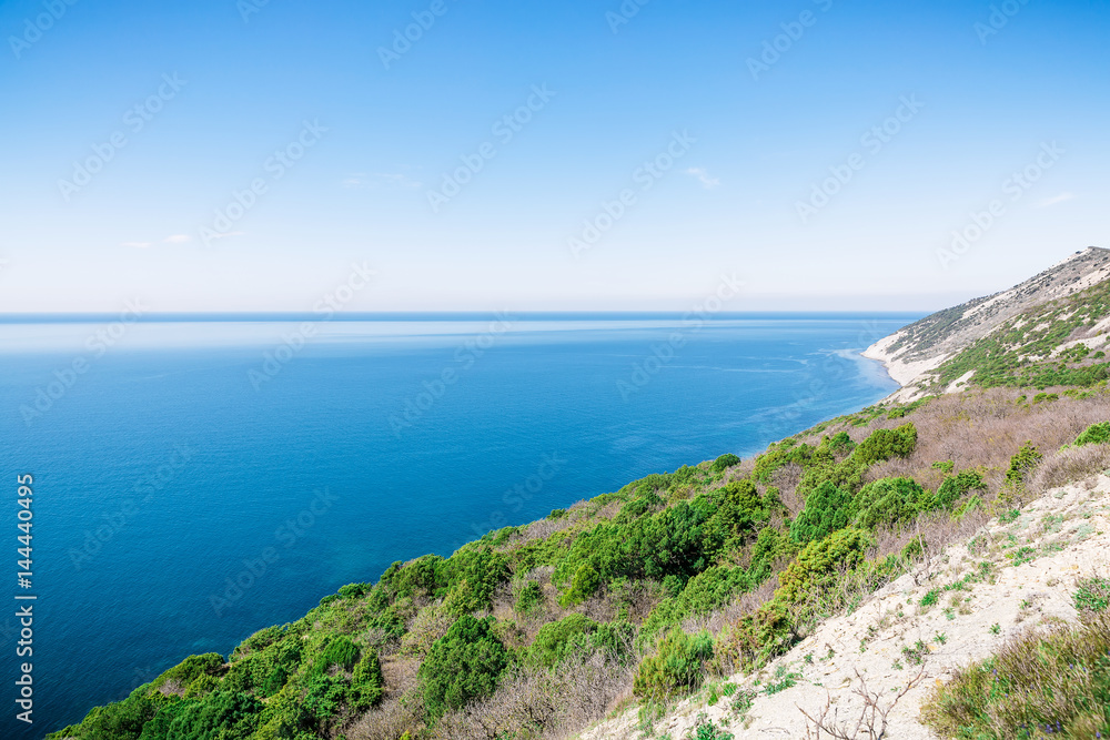 Blue ocean, cliff and trees in the Mediterranean. Sunny day on sea