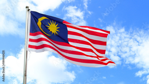 Malaysian national flag on a pole against bright blue sky.