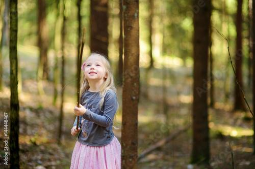Cute little girl having fun during forest hike on beautiful spring day.