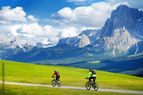 Tourists cycling in Seiser Alm, the largest high altitude Alpine meadow in Europe, stunning rocky mountains on the background. photo