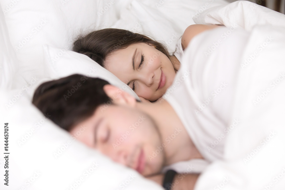 Happy couple resting together, enjoying soft bed and pleasant good dreams, beautiful girl smiling while sleeping with her boyfriend or husband between the sheets at home Happy couple resting together, enjoying soft bed and pleasant good dreams, beautiful girl smiling while sleeping with her boyfriend or husband between the sheets at home