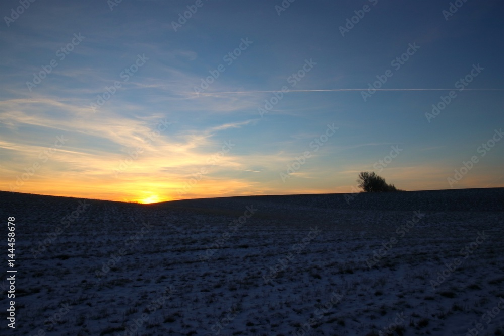 The sun rises behind a hill in February
