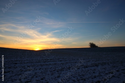 The sun rises behind a hill in February