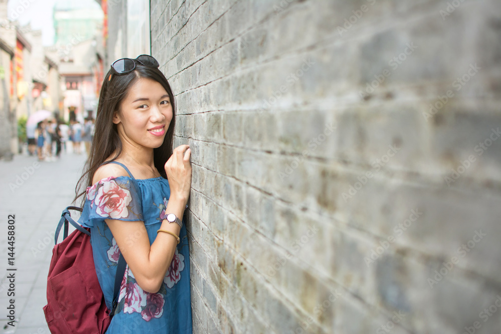 Asian girl standing by a stone wall Asian girl standing by a stone wall