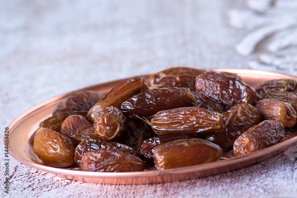 Fototapeta premium Useful food. Dried sweet dates on a round copper tray.