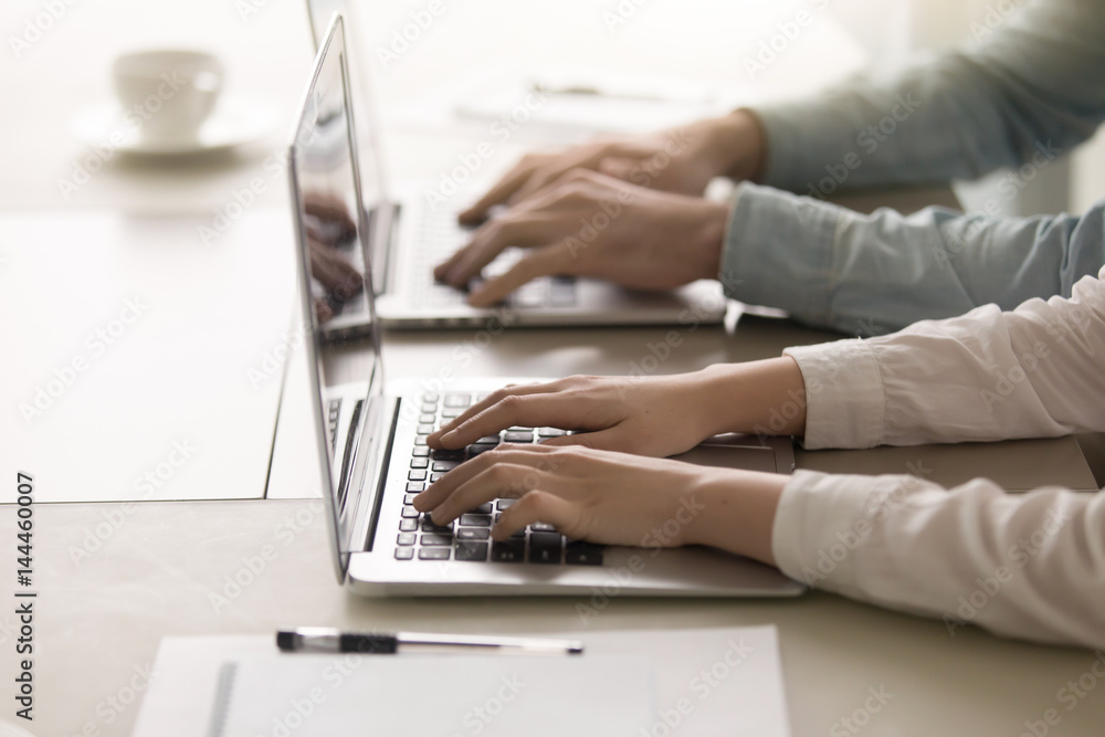 Man and woman working together on two laptops at home office interior. Close up view of female and male hands on keyboard, online support, educational on-line courses concept Man and woman working together on two laptops at home office interior. Close up view of female and male hands on keyboard, online support, educational on-line courses concept