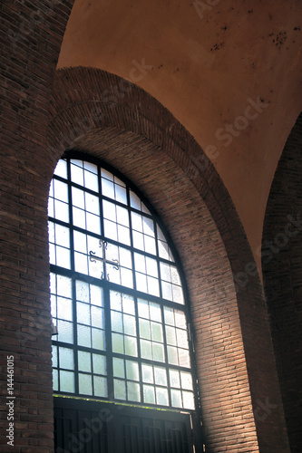 beautiful medieval arched window with black frames and brick archway