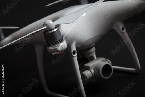 Close up of propeller of white drone (Quadrocopter) with camera on gimbal on dark background