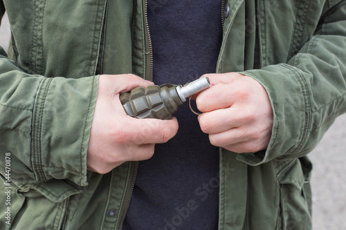Mężczyzna w wojskowej kurtce z granatem w dłoni