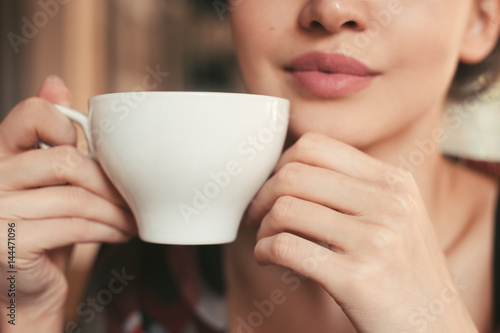 woman holding a cup tea in hand, sitting in the morning in a cafe