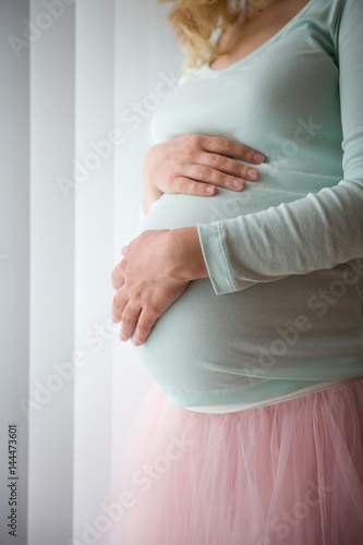 Closeup of pregnant woman's belly. Image of pregnant woman touching her belly with hands.