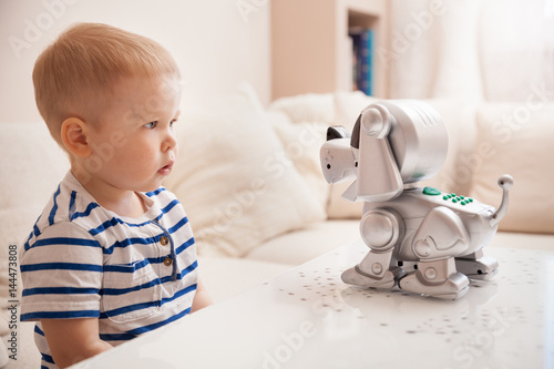 Adorable toddler boy playing with interactive toy. Child with toy robot dog. indoors. Activities for small children. Communication and digital concept.