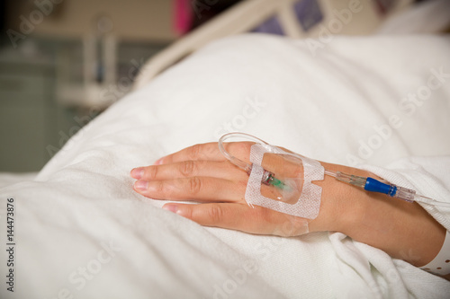 Tableau sur toile Close up hand of young patient with intravenous catheter for injection plug in hand during lying in the hospital bed