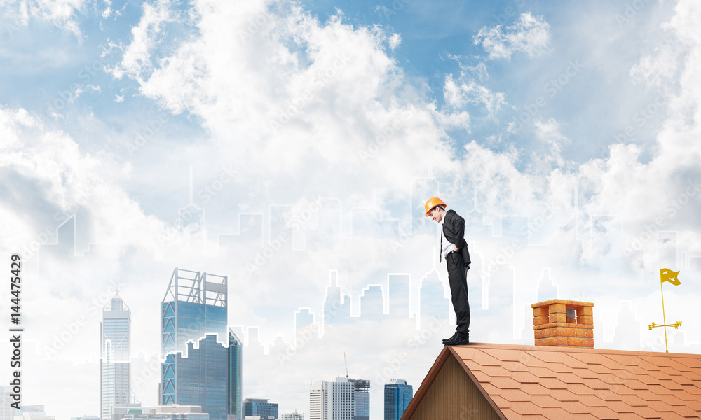 Engineer man standing on roof and looking down. Mixed media Engineer man standing on roof and looking down. Mixed media