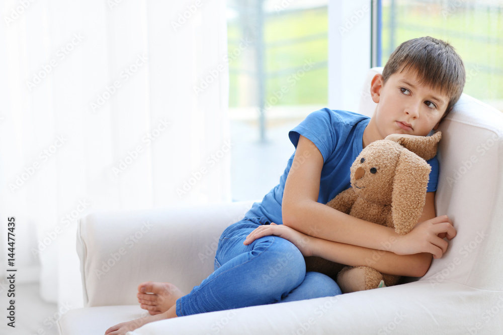 Sad little boy sitting in armchair at home Sad little boy sitting in armchair at home