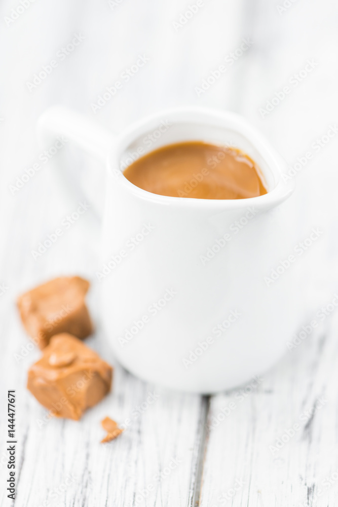 Portion of Caramel Sauce on wooden background (selective focus) Portion of Caramel Sauce on wooden background (selective focus)