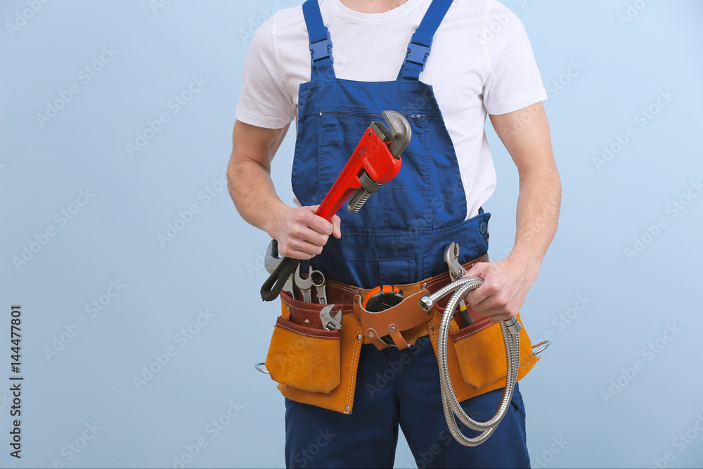 Handsome young plumber with tools on color background Handsome young plumber with tools on color background