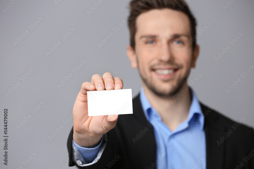 Handsome young man with business card on grey background, closeup Handsome young man with business card on grey background, closeup