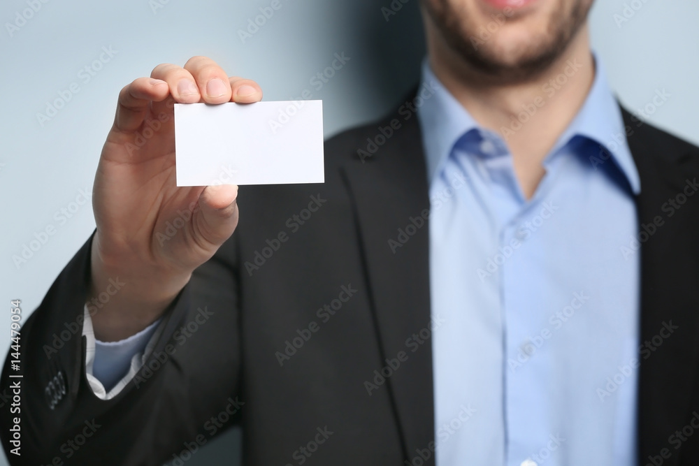 Young man with business card on color background, closeup Young man with business card on color background, closeup