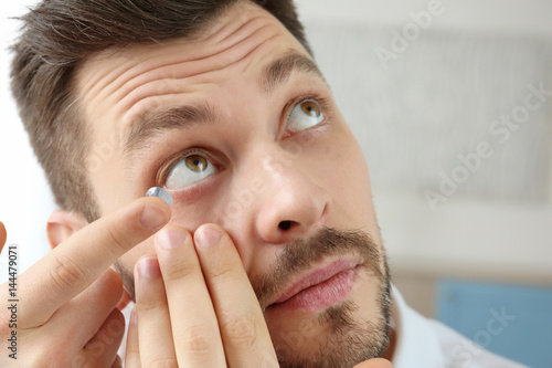 Young man putting contact l...