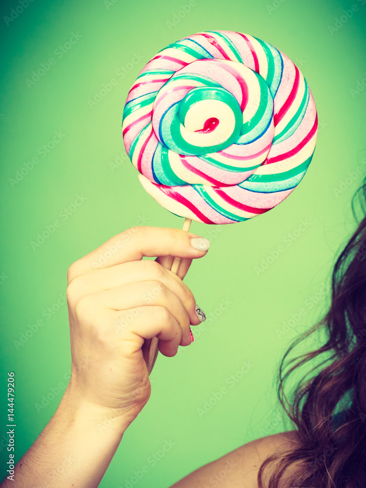 Female hand holds colorful lollipop candy Female hand holds colorful lollipop candy