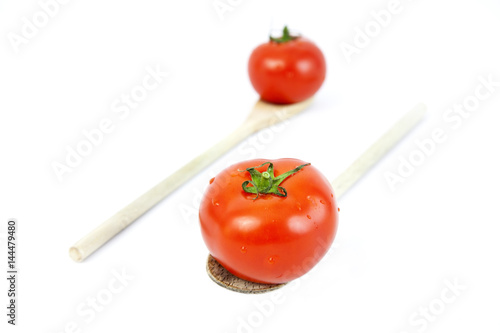 Red ripe tomatoes on wooden spoons. Focus on foreground tomato. Isolated.