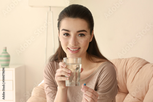 Beautiful young woman taking pill at home