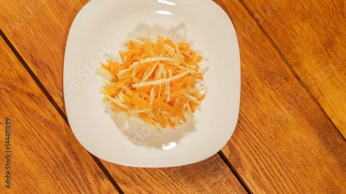 Vegetable salad of carrot and cabbage in white plate on wooden background close up. Vegetarian healthy salad in vegetable oil