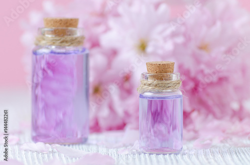beautiful spa composition, aromatherapy with essential oils, fresh sakura on pink background, selective focus