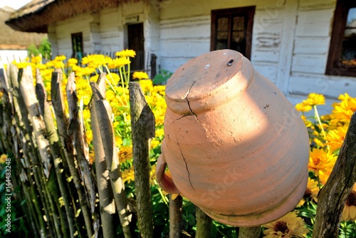 rural landscape with a clay pot on a fence and flowers