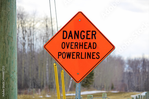 Canvas Print Danger overhead powerline sign beside a power pole