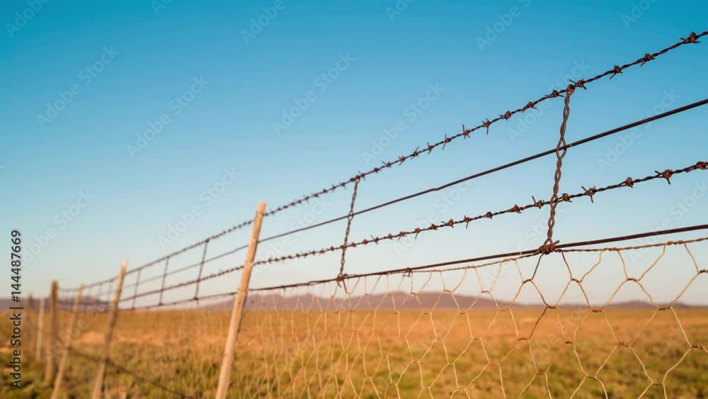 A static timelapse at sunrise of a close-up jackal and sheep fence on a free range Karoo farm with a shadow slowly moving across A static timelapse at sunrise of a close-up jackal and sheep fence on a free range Karoo farm with a shadow slowly moving across