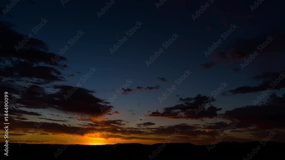 A static timelapse at sunset with a dramatic cloudy sky and contrasty blue and orange glow as the shot dip to black