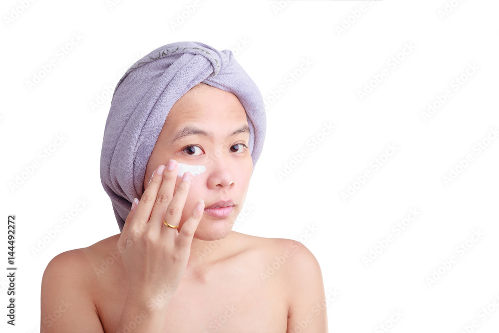 Beauty skin care cosmetics and health concept. Closeup Asian young woman applying cream on her face isolated on white color background with clipping path. Beauty skin care cosmetics and health concept. Closeup Asian young woman applying cream on her face isolated on white color background with clipping path.