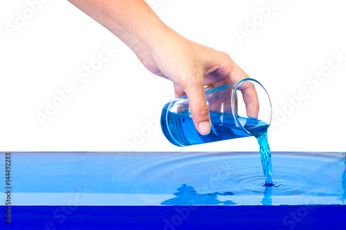 hand holding a glass of water. Pouring blue liquid on isolated white background with clipping path