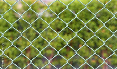 Green metal grille fence and defocused nature background