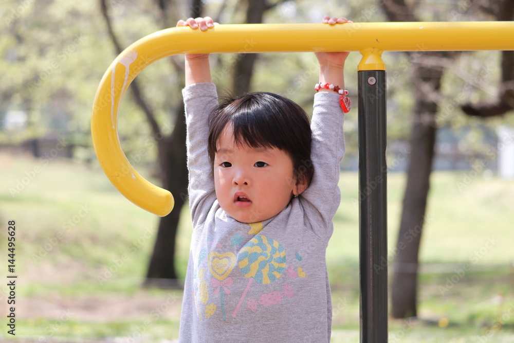 Fototapeta premium 遊具にぶら下がる女の子