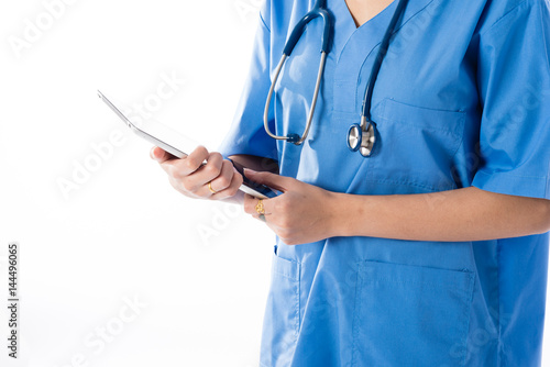 Female Asian nurse using a digital tablet & wearing a blue coat mon white background