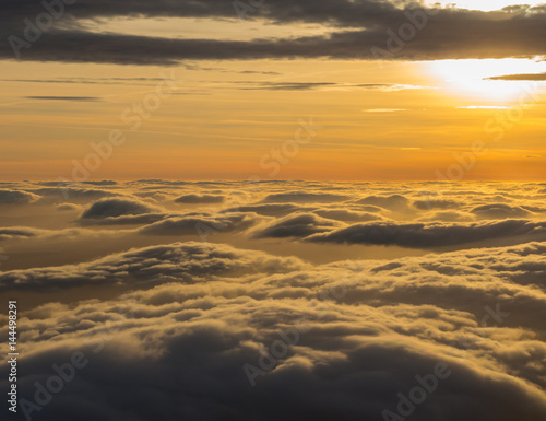 Aerial view from the airplane to a massive sea of clouds at the sunset