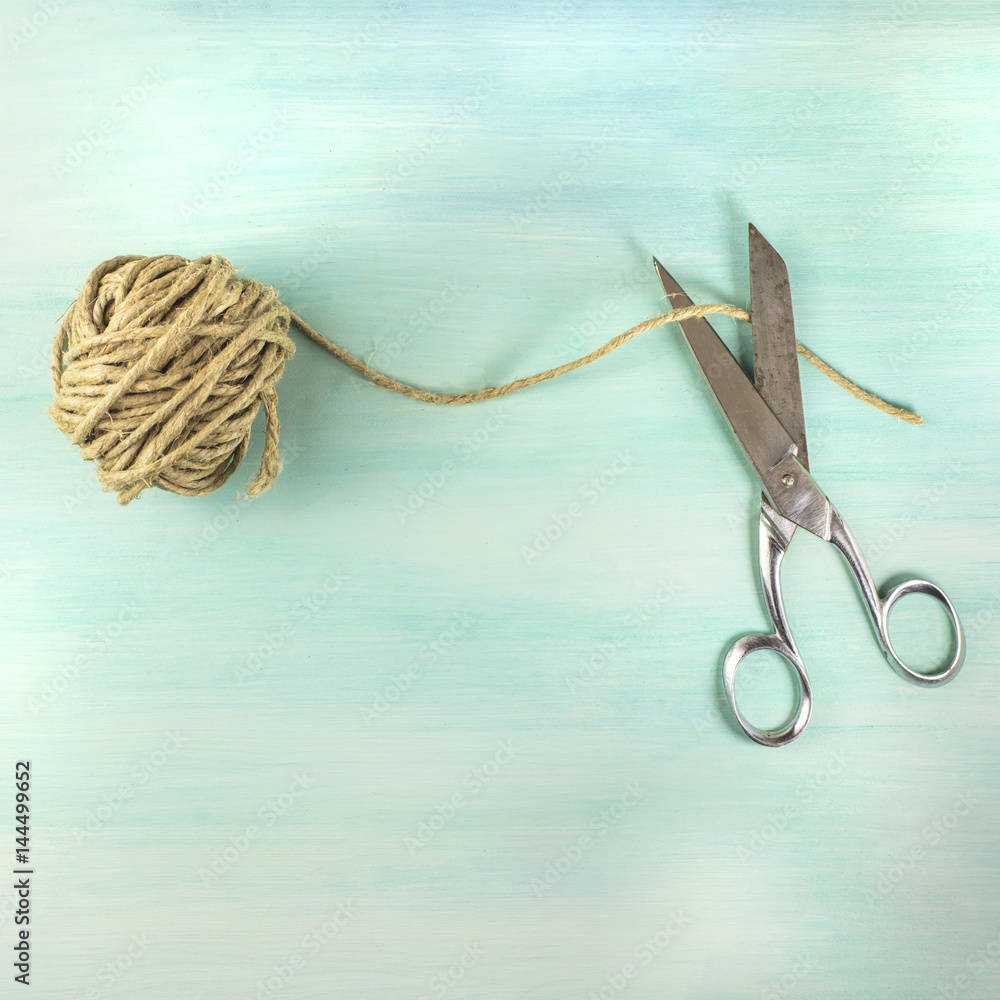 Vintage scissors and roll of twine on teal background