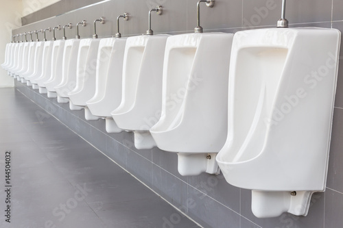 Row of outdoor urinals on grey wall in men public toilet