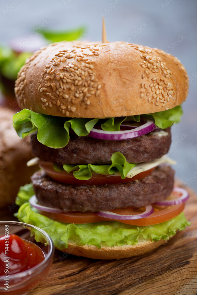 Double beef burger on a white sesame bun, close-up with shallow depth of field, selective focus Double beef burger on a white sesame bun, close-up with shallow depth of field, selective focus