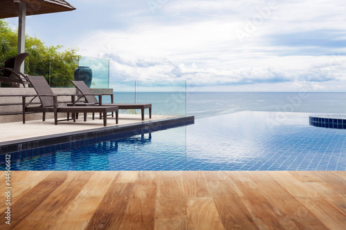 Wood table top on Beach chair in outdoor with swimming pool and sea view andaman sea. © panya99