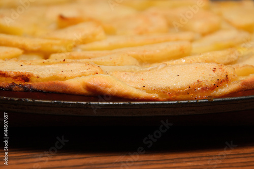 Close up photograph of a freshly made apple pie with apple slices