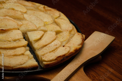 Homemade apple pie, and piece of pie with apple slices on cook board.