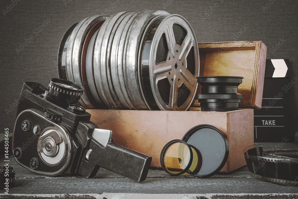 Obraz premium Reels with films in a wooden box, lens and an old movie camera